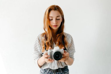 Kızıl saçlı kadın fotoğrafçı ışık stüdyosunda fotoğraf çekiyor. Hobi konsepti