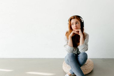 Duyarlı kadın odada yerde kulaklıkla müzik dinliyor. İnsanların yaşam tarzı konsepti. Kişisel gelişim kavramı