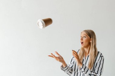 Güzel sarışın kız ofiste kahve fincanıyla oynuyor.