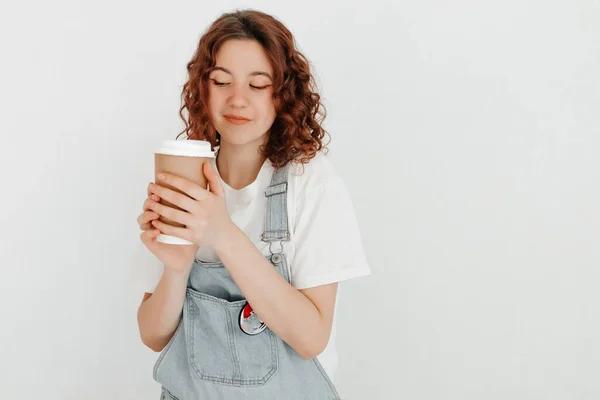 Young Woman Overalls Holding Hot Cup Coffee White Wall Free — Stock Photo, Image