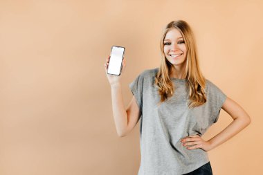 Kız bir cep telefonu gösterisi yapıyor. Beyaz maket kullanılıyor.