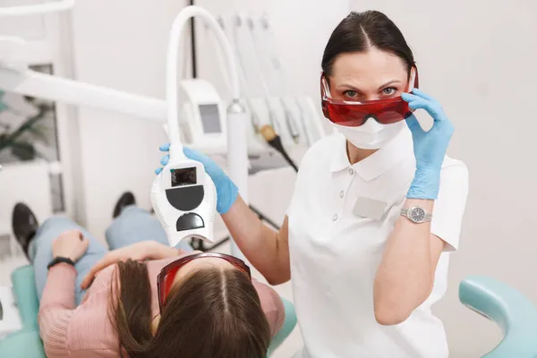 Жінка Стоматолог Дивиться Камеру Над Захисними Окулярами Робить Відбілювання Зубів — стокове фото