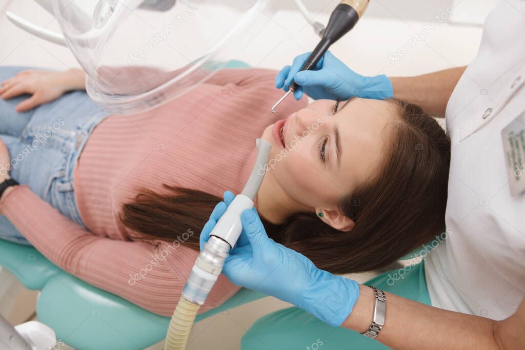 Top view shot of a young woman at dental clinic, getting professional teeth cleaning