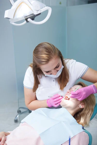 Pionowe Ujęcie Profesjonalnego Dentysty Badającego Zęby Pacjentki — Zdjęcie stockowe