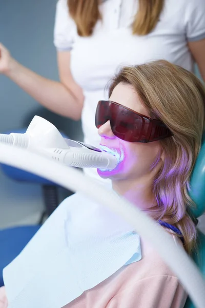 Pionowe Ujęcie Kobiety Noszącej Okulary Ochronne Podczas Zabiegu Wybielania Zębów — Zdjęcie stockowe