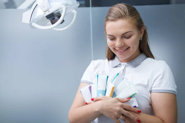 可爱的年轻女牙医拥抱着许多牙膏管 开心地微笑着 复制空间 — 图库照片