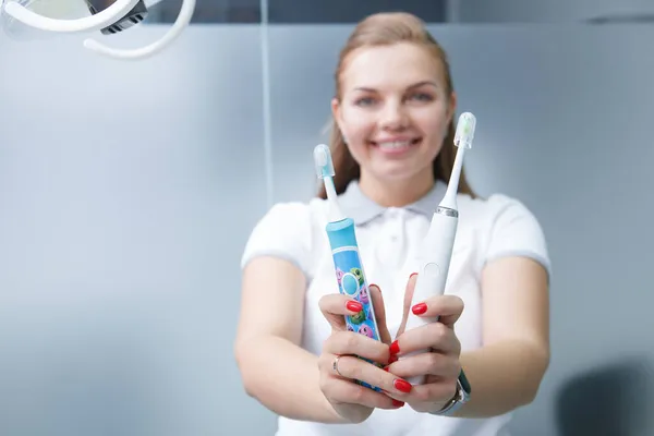 有选择地把重点放在电动牙刷上快乐的女牙医对着摄像机 — 图库照片