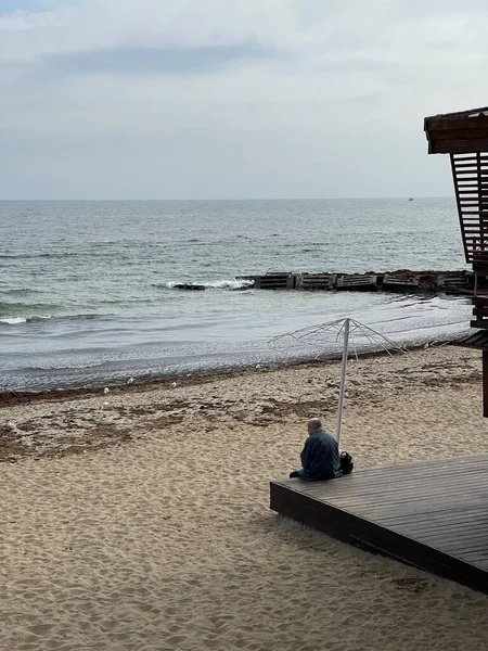 Vertikalt Skott Figur Oigenkännlig Man Tittar Vattnet Sitter Vid Stranden — Stockfoto