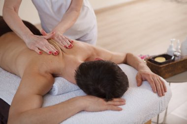Spa merkezinde rahatlayan tanınmayan bir adam, profesyonel sırt masajı yaptırıyor.