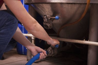 Tanınmayan bir adam çelik bir tanka hortum bağlıyor.