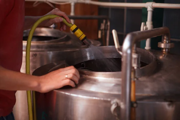 一名酿酒厂技师用水管冲洗啤酒罐的剪影 — 图库照片