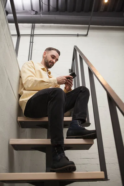 Düşük Açılı Akıllı Telefon Kullanan Bir Adamın Otel Odasındaki Merdivenin — Stok fotoğraf