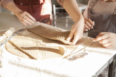 Kil parçasıyla çalışan tanınmayan çocuk ve profesyonel seramikçi.