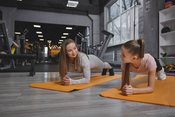 Lovely Teenage Girl Smiling Her Personal Trainer While Doing Plank — Zdjęcie stockowe