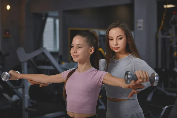 Professional Sportswoman Supervising Teenage Girl Gym Workout Doing Dumbbells Exercise — Fotografia de Stock