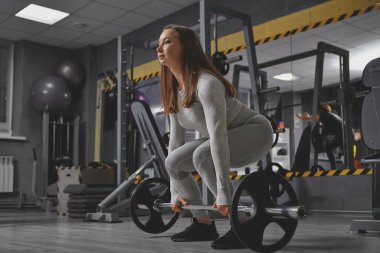 Sporcu kadın spor salonunda ağırlık kaldırma egzersizi yapıyor.