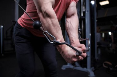 Damarları kapalı kaslı kollar, kablo çapraz spor makinesinde vücut geliştirici egzersizleri.