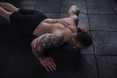 Ripped tattooed sportsman doing push ups at gym