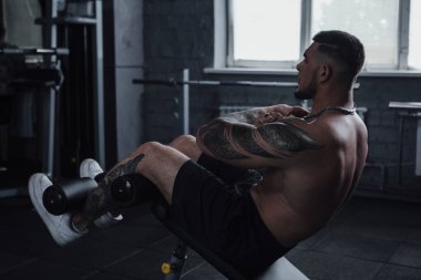Big muscular male bodybuilder doing abs workout at the gym