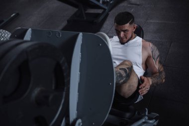 Top view shot of a huge strong muscular male athlete doing leg press workout at gym, looking concentrated