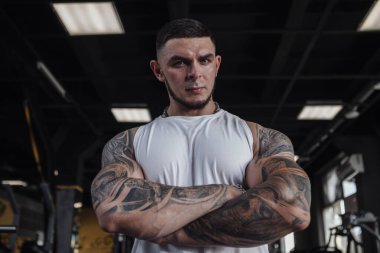 Low angle portrait of a strong muscular tattooed bodybuilder looking to the camera powerfully