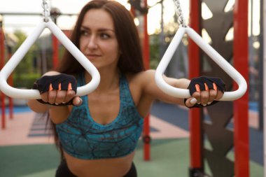 Sporcu kadının tuttuğu jimnastik yüzüklerine odaklan, dışarıda egzersiz yap.