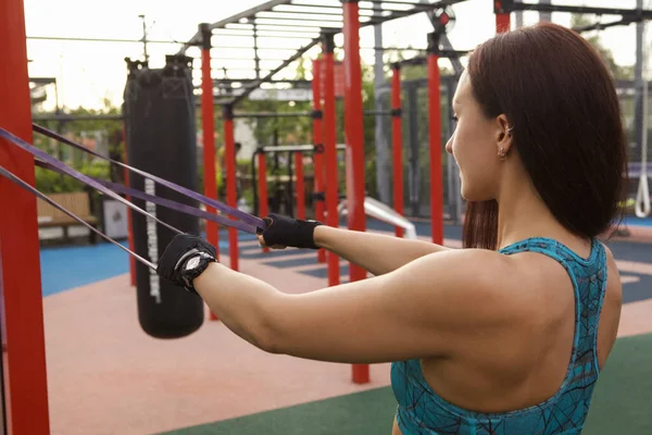 一名健康的女运动员在室外与阻力带一起锻炼时的后视镜照片 — 图库照片