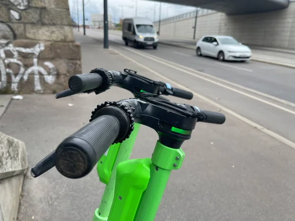 Şehre park etmiş elektrikli scooter kulplarının yakın çekim görüntüleri, arka planda arabalar.