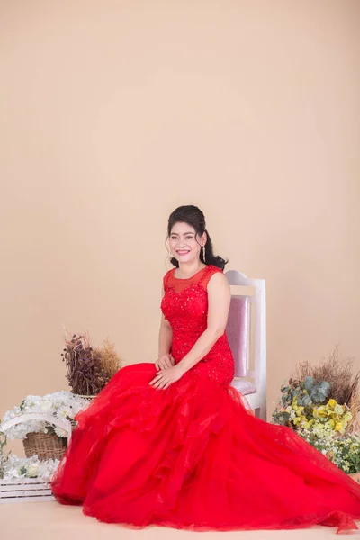 Hermosa Asiático Adulto Mujer Rojo Vestido Sentado Silla Cerca Flores — Foto de Stock