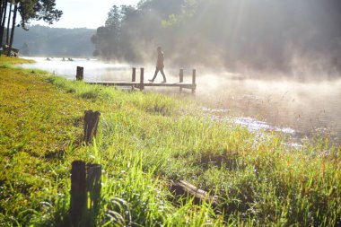 Nehirdeki ahşap iskelede bir adam