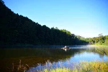Güneşli bir günde nehirde yüzen tekne 
