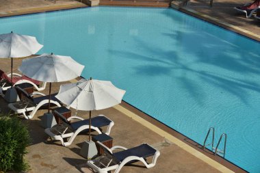 Lüks otellerde şemsiye ve sandalyelerle yüzme havuzu.