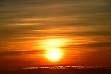 Güneş sık bir ormanın arkasında batıyor ve ardından dağlar geliyor.