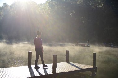 Güneşli bir günde Nehirdeki ahşap iskelede bir kadın