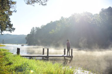 Güneşli bir günde Nehirdeki ahşap iskelede bir kadın