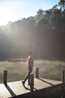 Güneşli bir günde Nehirdeki ahşap iskelede bir kadın