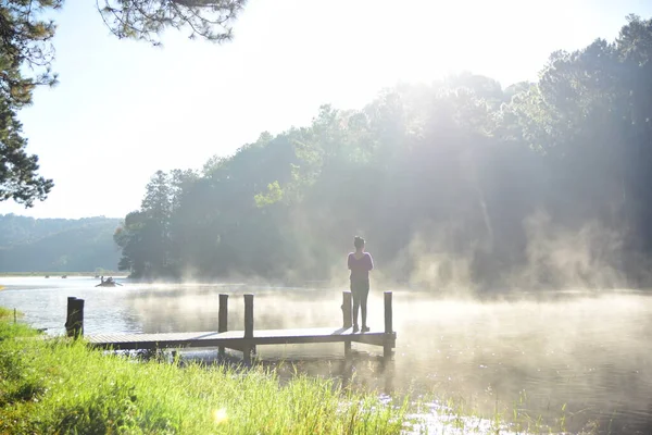 Güneşli bir günde Nehirdeki ahşap iskelede bir kadın