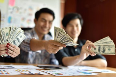 Ofisinde dolar banknotları olan Asyalı işadamları