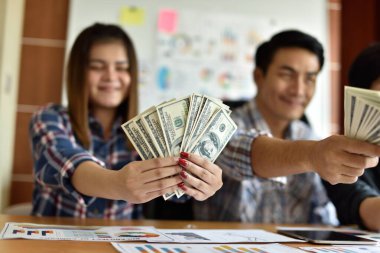 Ofisinde dolar banknotları olan Asyalı işadamları