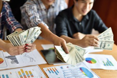 Ofisinde dolar banknotları olan Asyalı işadamları