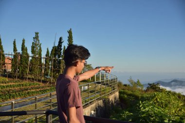 Asyalı adam dağları işaret ediyor.