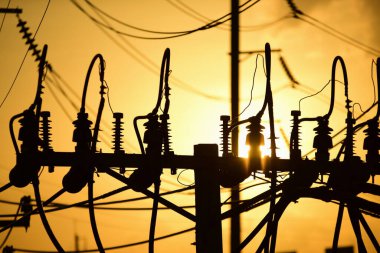 Günbatımında yüksek voltaj kulesi ve elektrik direkleri
