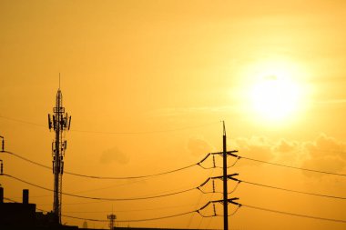 Günbatımında yüksek voltaj kulesi ve elektrik direkleri
