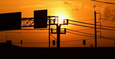 Günbatımında elektrik direkleri ve yol reklam panoları