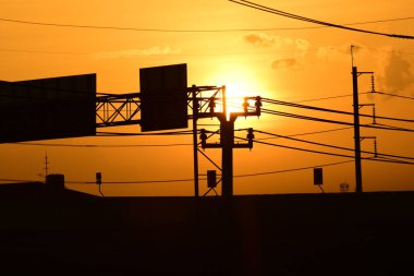Günbatımında elektrik direkleri ve yol reklam panoları