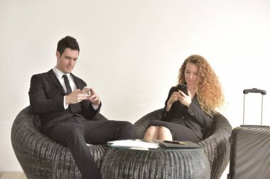 İşadamı ofiste iş kadınıyla çalışıyor. Müşterilerle mesajlaşıyor. Akıllı telefonlar kullanıyor..