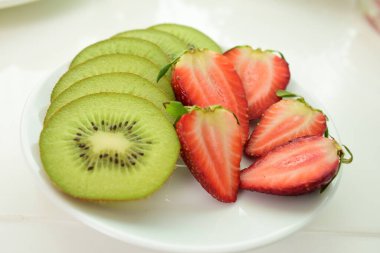 Beyaz bir tabakta taze çilek ve kivi.