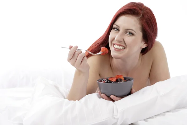 Donna a letto mangiare frutta — Foto Stock