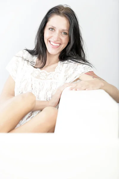 Woman sitting on white sofa — Stock Photo, Image