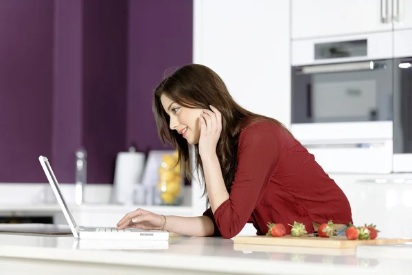 Woman in kitchen reading recipe — Stock Photo, Image